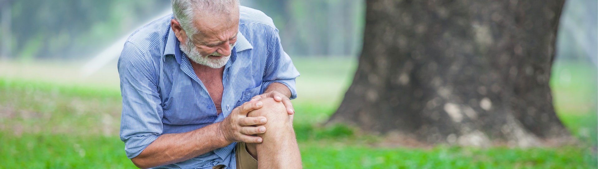 man kneeling looking at hurt knee